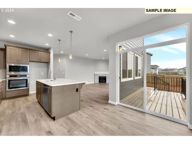 a large kitchen with kitchen island a large counter top space a sink stainless steel appliances and cabinets