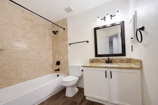 a bathroom with a granite countertop sink toilet and shower