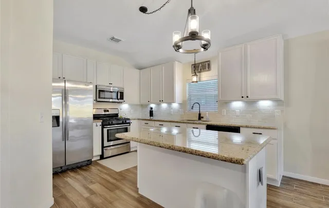 a kitchen with stainless steel appliances granite countertop a sink refrigerator and cabinets