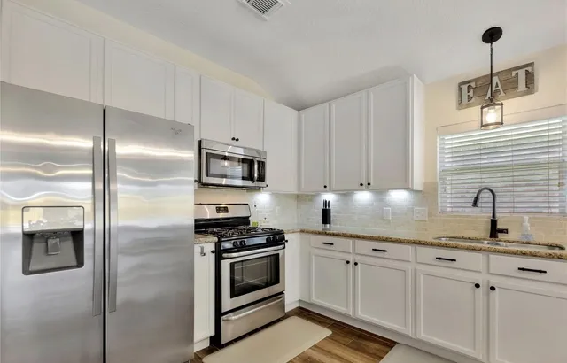 a kitchen with white cabinets and appliances