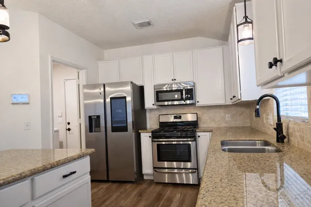 a kitchen with stainless steel appliances granite countertop a refrigerator sink and stove
