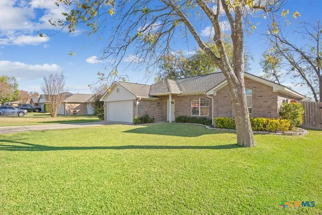 a view of a house next to a big yard with large tree