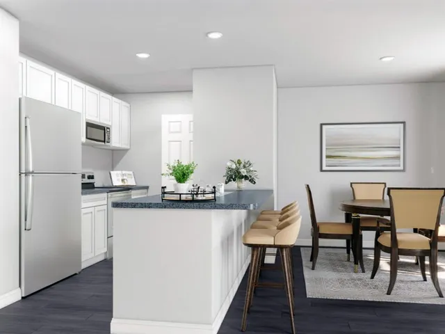 a kitchen with stainless steel appliances granite countertop a dining table chairs refrigerator and sink