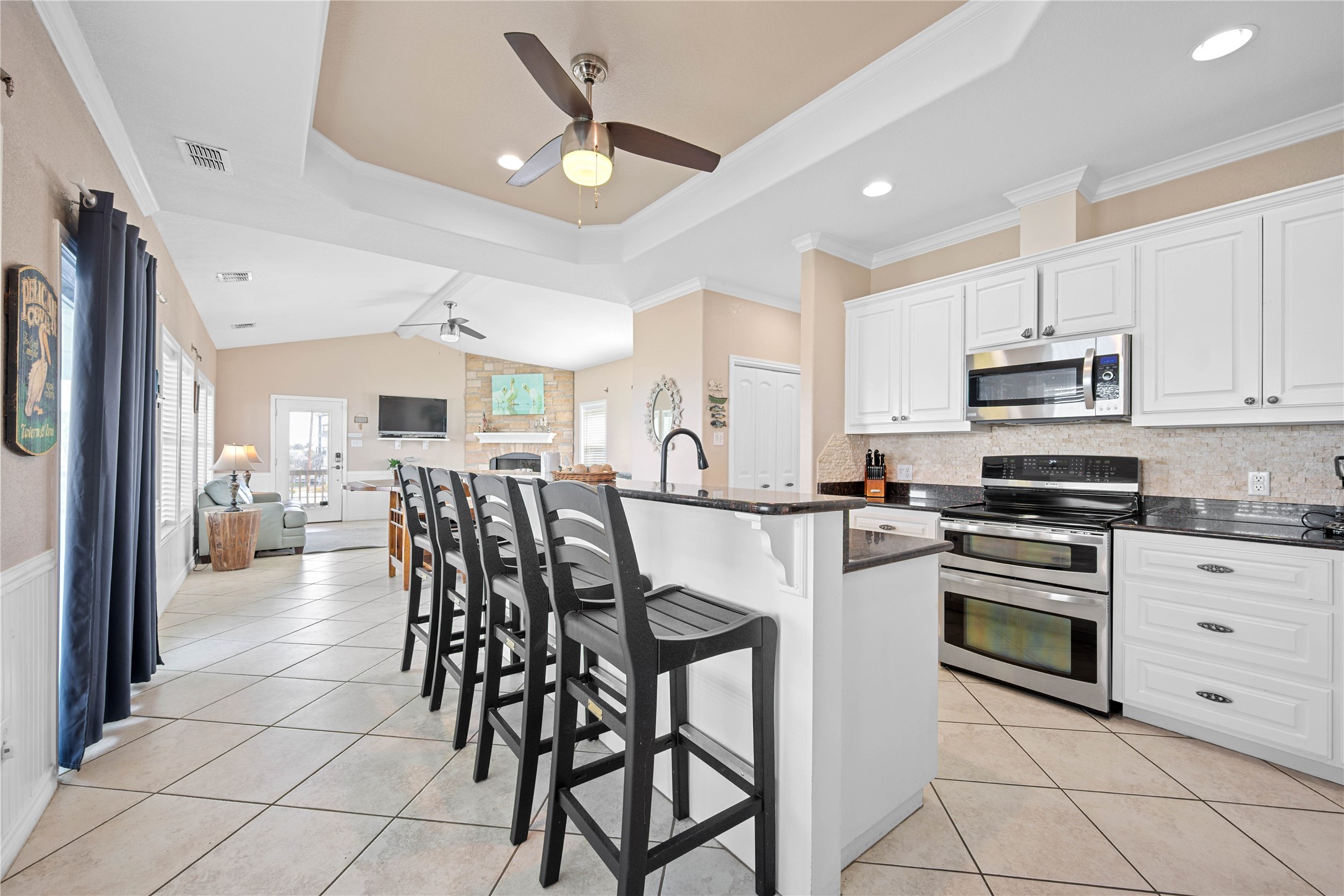 740 Copano Cove Road Rockport, TX 78382 - Photo 19 of 35 a kitchen with stainless steel appliances kitchen island granite countertop a stove a refrigerator a stove a dining table and chairs with wooden floor