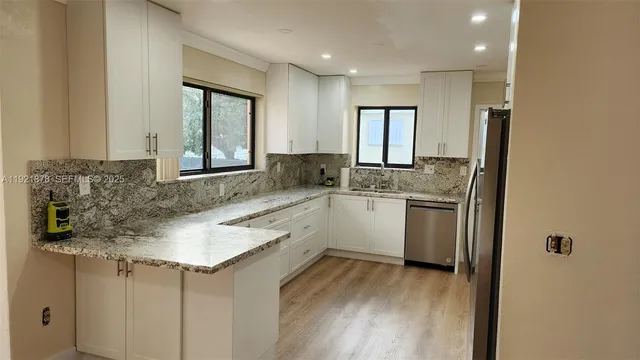 a kitchen with granite countertop white cabinets and window