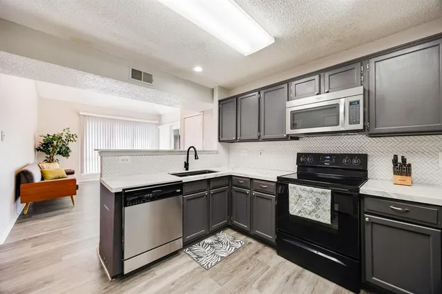 a kitchen with stainless steel appliances granite countertop a sink stove and microwave