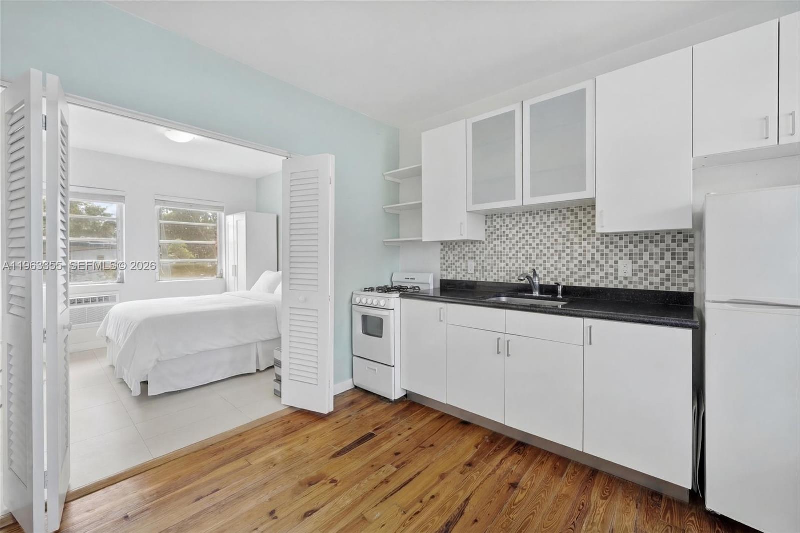 1925 Washington Avenue, Unit 21 Miami Beach, FL 33139 - Photo 4 of 16 a kitchen with granite countertop white cabinets and white appliances