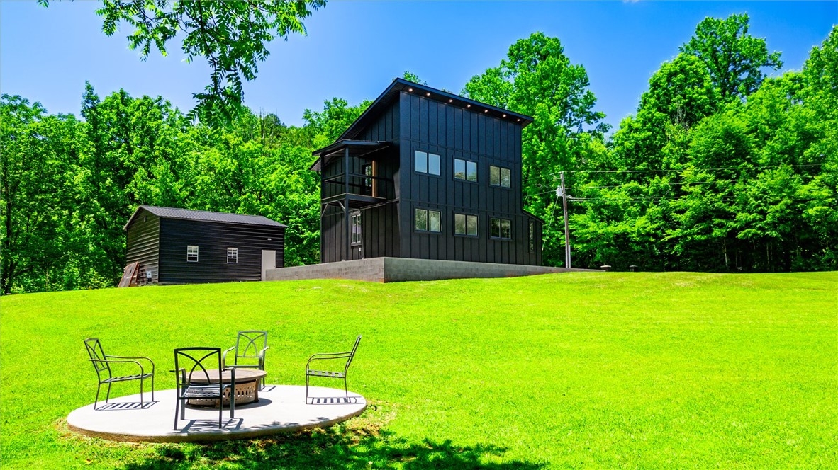 159 Cherokee Trail Easley, SC 29640 - Photo 2 of 38 Perched on a grassy expanse, this contemporary black-clad residence offers a serene escape with its fire pit and surrounding greenery.