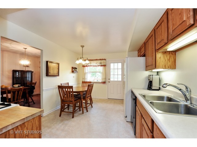 439 Weidner Road Buffalo Grove, IL 60089 - Photo 7 of 23 a kitchen with a dining table chairs and white appliances