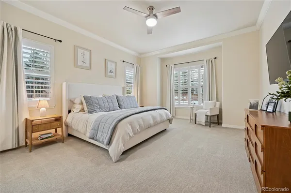 a spacious bedroom with a bed and a flat tv screen on dresser
