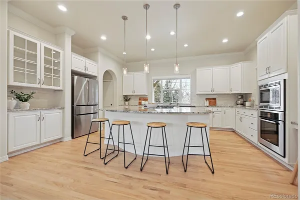 a kitchen with stainless steel appliances granite countertop a refrigerator a stove top oven and a dining table with wooden floor