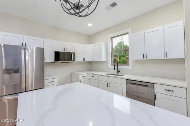 a kitchen with white cabinets and stainless steel appliances