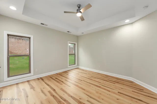 a view of empty room with wooden floor and fan