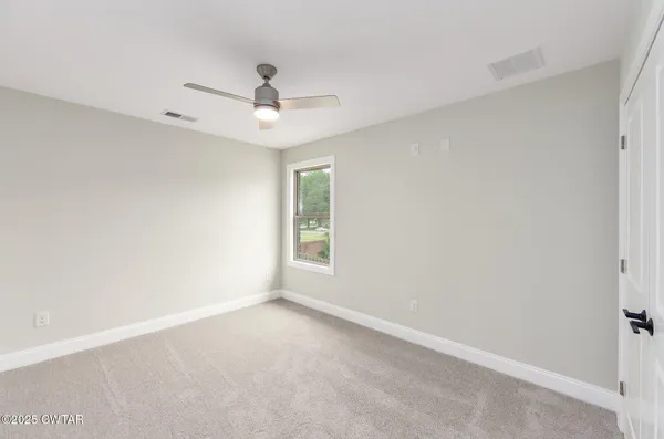 an empty room with a window and ceiling fan