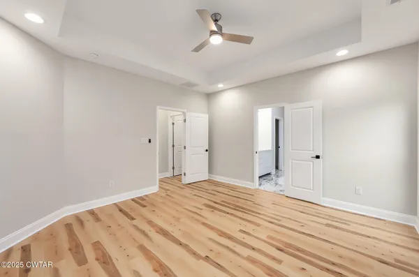 a view of empty room with wooden floor and fan
