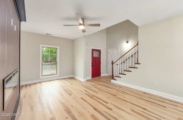 a view of empty room with wooden floor and fan
