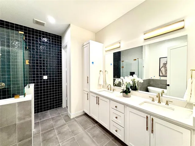 a bathroom with a double vanity sink a toilet and shower