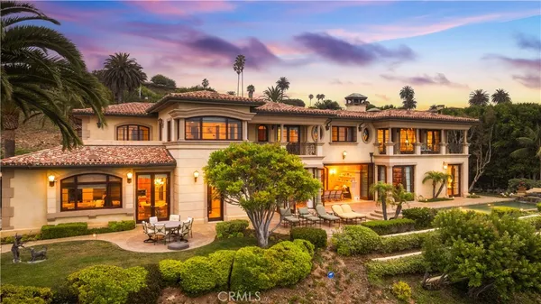 a view of a white house with a big yard and potted plants