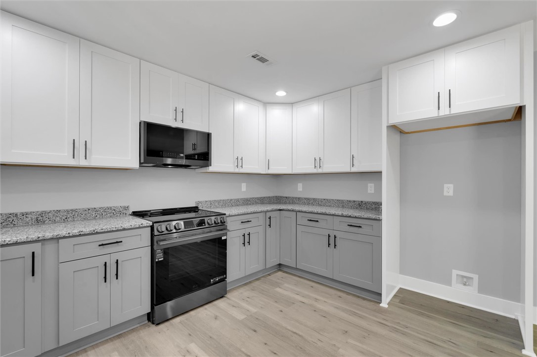 1747 A State Rd S-4-97 Anderson, SC 29621 - Photo 17 of 47 A contemporary kitchen features gray shaker-style cabinetry with granite counters, paired with new stainless steel appliances.