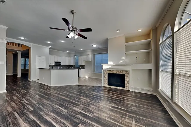 a view of a kitchen with kitchen island wooden floor and a ceiling fan