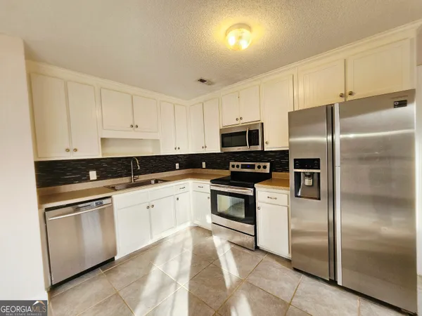 a kitchen with cabinets stainless steel appliances and a counter space