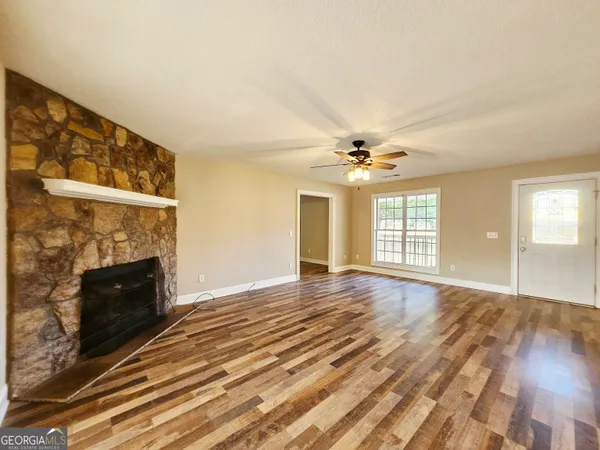 a view of an empty room with wooden floor fireplace and a window