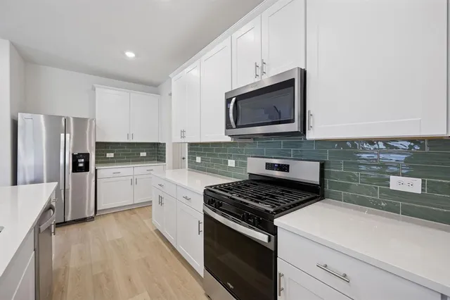 a kitchen with stainless steel appliances white cabinets and a stove top oven