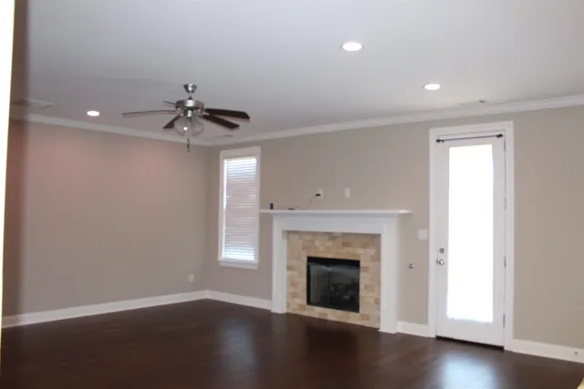 a view of an empty room with wooden floor fireplace and a window