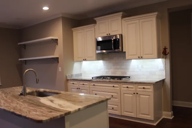 a kitchen with granite countertop white cabinets and stainless steel appliances