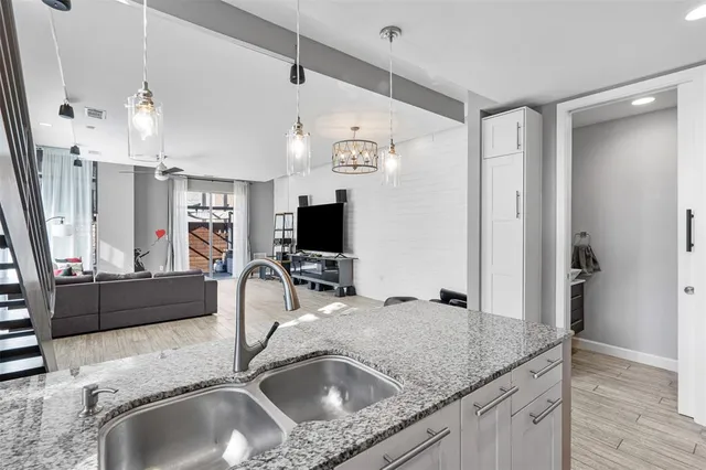a kitchen with granite countertop a sink dishwasher and a refrigerator with wooden floor