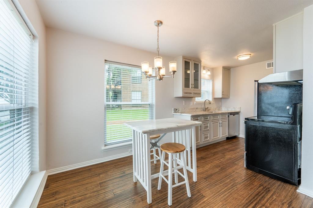 4610 Chaha Road, Unit 106 Garland, TX 75043 - Photo 12 of 25 a kitchen with a table chairs a sink dishwasher window and cabinets