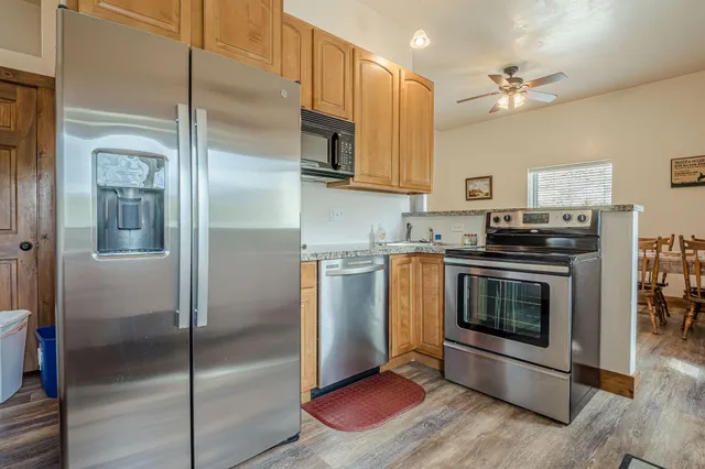 a kitchen with stainless steel appliances granite countertop a stove top oven a sink dishwasher and cabinets with wooden floor