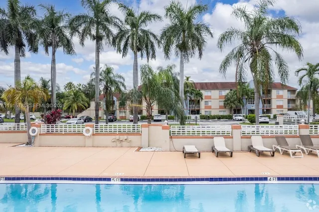 a view of a swimming pool with a lawn chairs and palm tree