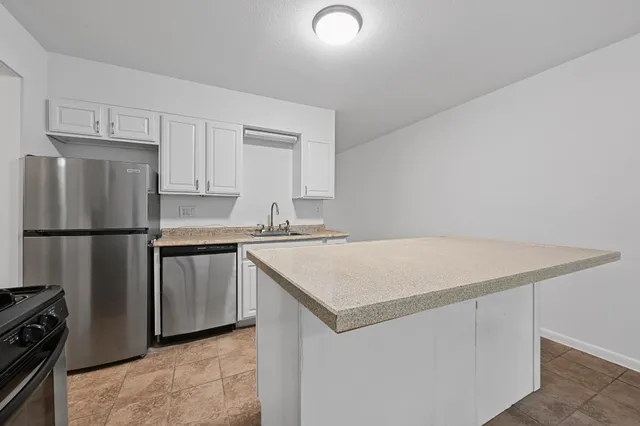 a kitchen with a sink a refrigerator and white cabinets