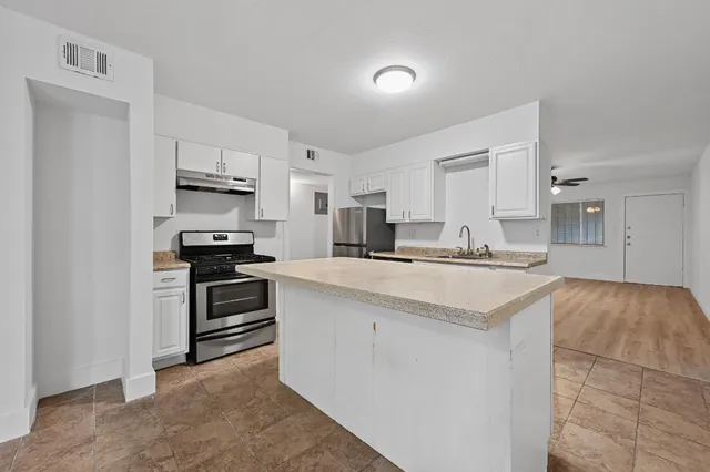 a kitchen with stainless steel appliances a sink stove refrigerator and cabinets