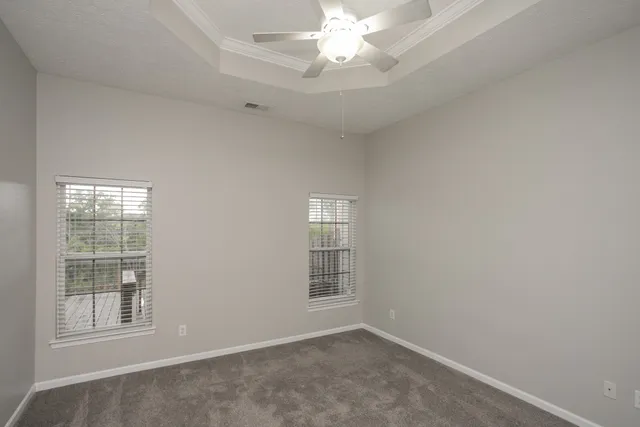an empty room with windows and chandelier fan