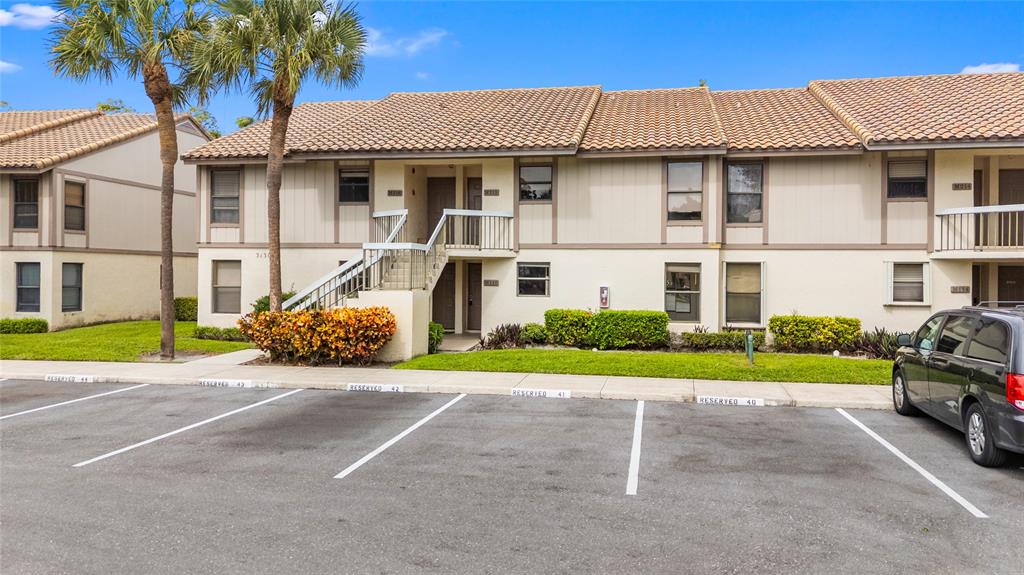 3130 Millwood Terrace, Unit 115 Boca Raton, FL 33431 - Photo 2 of 34 a white house with a small yard and large trees