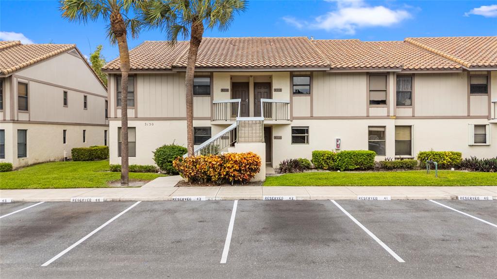 3130 Millwood Terrace, Unit 115 Boca Raton, FL 33431 - Photo 3 of 34 a front view of a house with a garden and plants