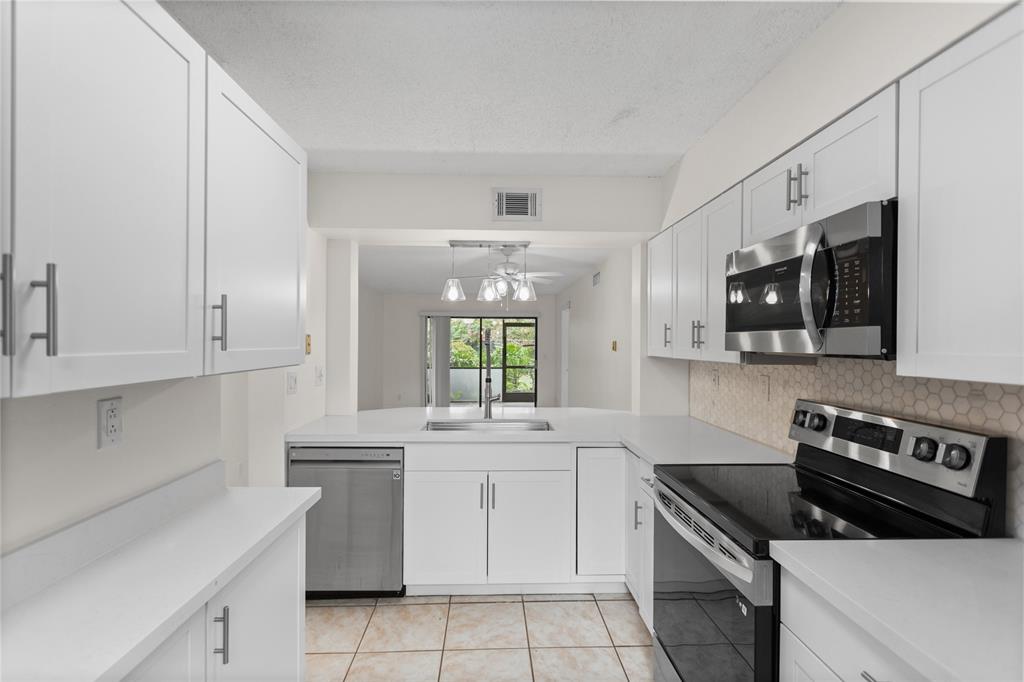 3130 Millwood Terrace, Unit 115 Boca Raton, FL 33431 - Photo 5 of 34 a kitchen with stainless steel appliances white cabinets and a sink