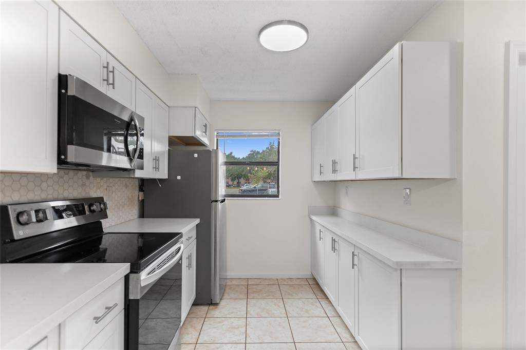 3130 Millwood Terrace, Unit 115 Boca Raton, FL 33431 - Photo 6 of 34 a kitchen with a sink a stove and cabinets