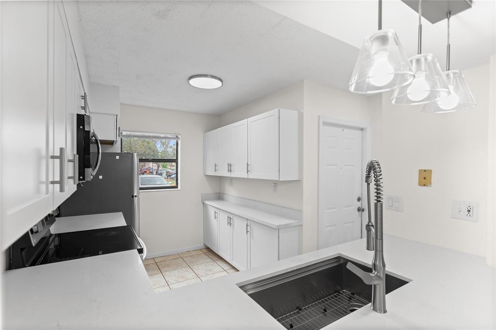 3130 Millwood Terrace, Unit 115 Boca Raton, FL 33431 - Photo 7 of 34 a kitchen with stainless steel appliances granite countertop a sink a stove a refrigerator cabinets and chairs