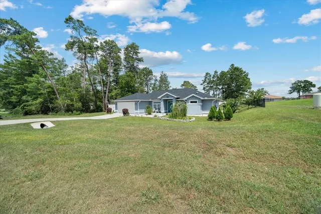 an aerial view of a residential houses with outdoor space and trees
