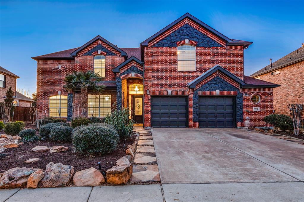 View of front of home with brick siding, concrete driveway, fence, and an attached garage