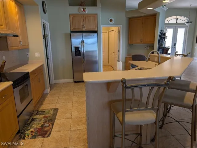 a kitchen with stainless steel appliances wooden floor dining table chairs and a sink