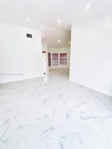 a view of a kitchen with kitchen island a sink wooden floor and entryway