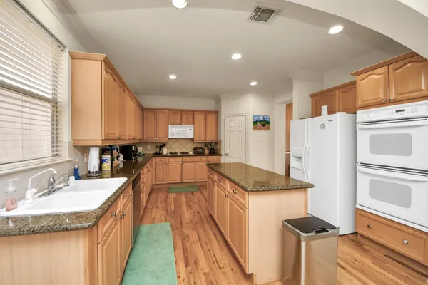 a large kitchen with stainless steel appliances granite countertop a stove a sink dishwasher and cabinets with wooden floor