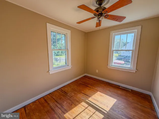 a view of an empty room with window and a chandelier fan