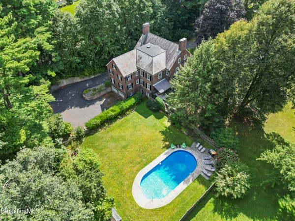 an aerial view of a house with swimming pool and outdoor seating