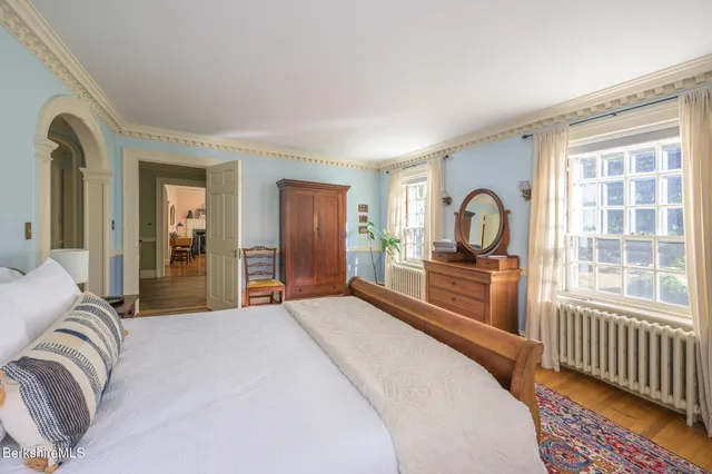 a spacious bedroom with a bed a dresser and windows