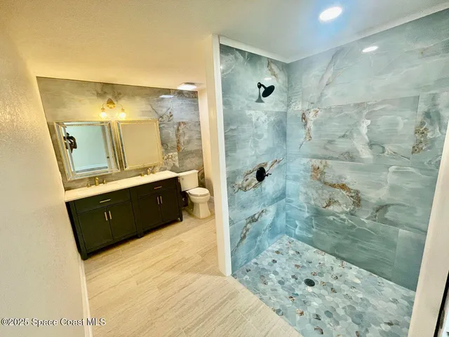 a bathroom with a double vanity sink toilet mirror and shower